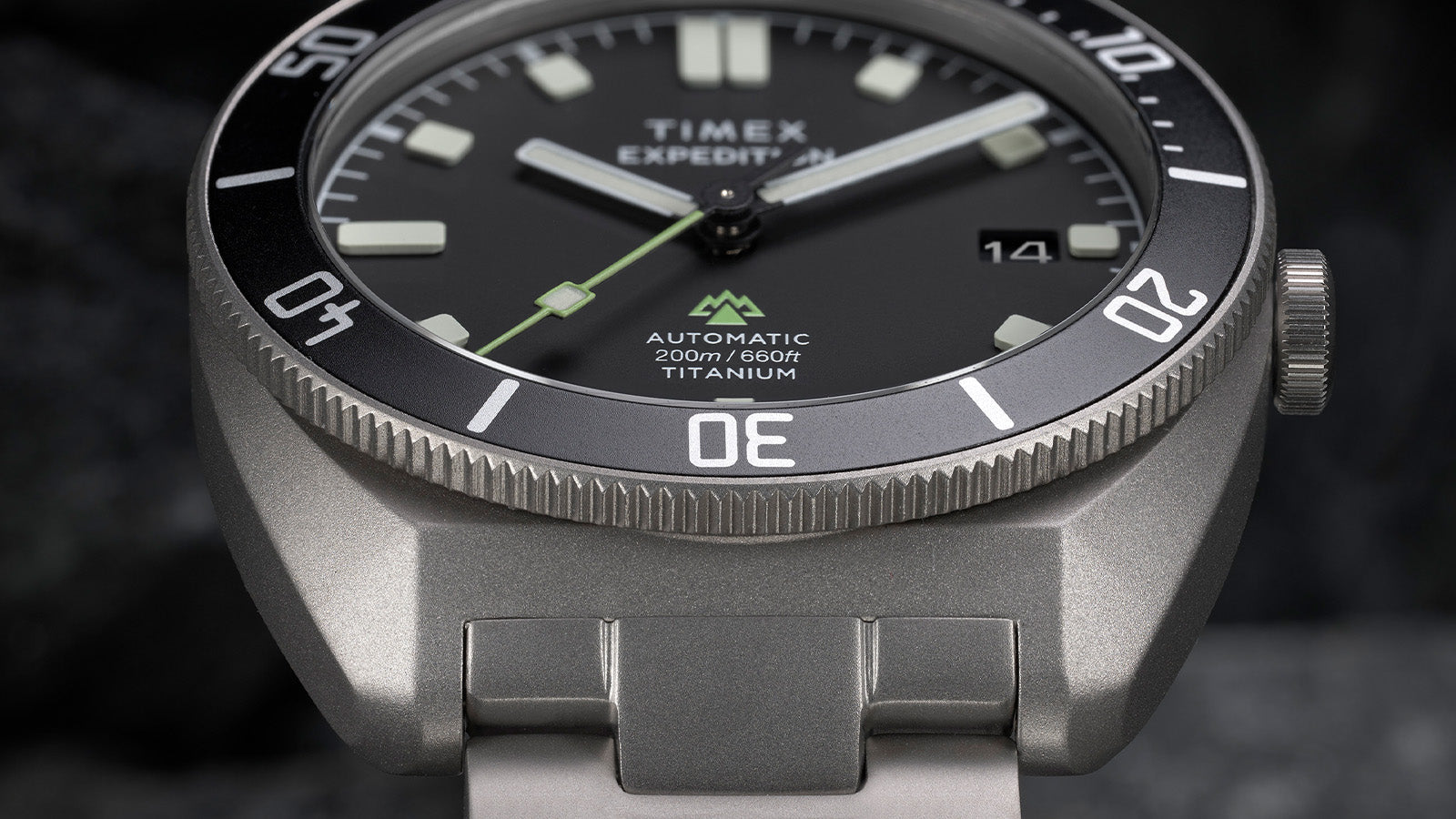 Macro close-up of the dial and bezel detailing the luminous hands, green seconds hand, and textured bezel edge.