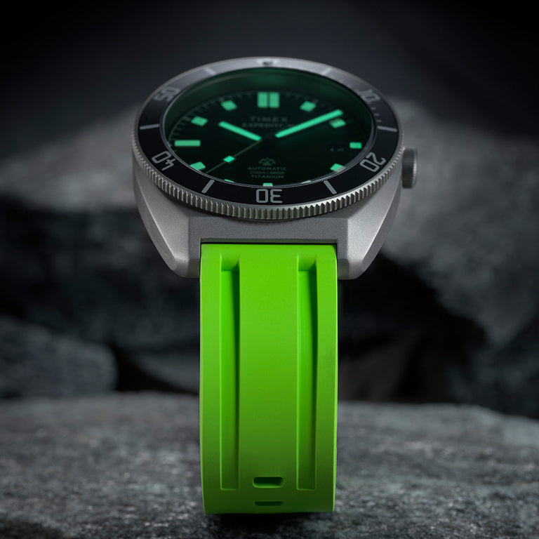 Low-light close-up of the Expedition® Pioneer Titanium Automatic showing luminous hands and hour markers glowing against the black dial.