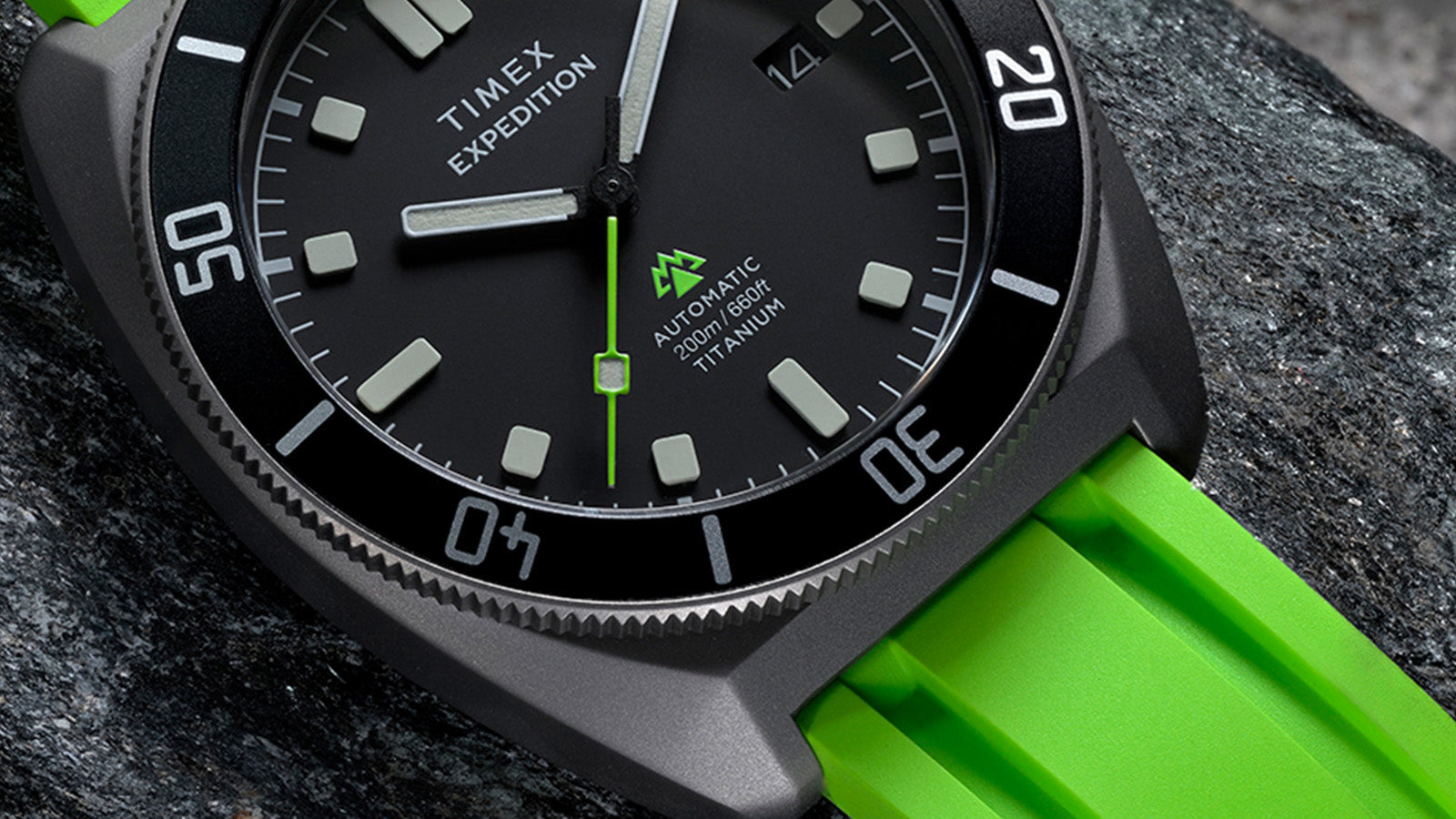 Close-up of the dial displaying “Automatic 200m/660ft Titanium” text, bold hour markers, and green seconds hand.