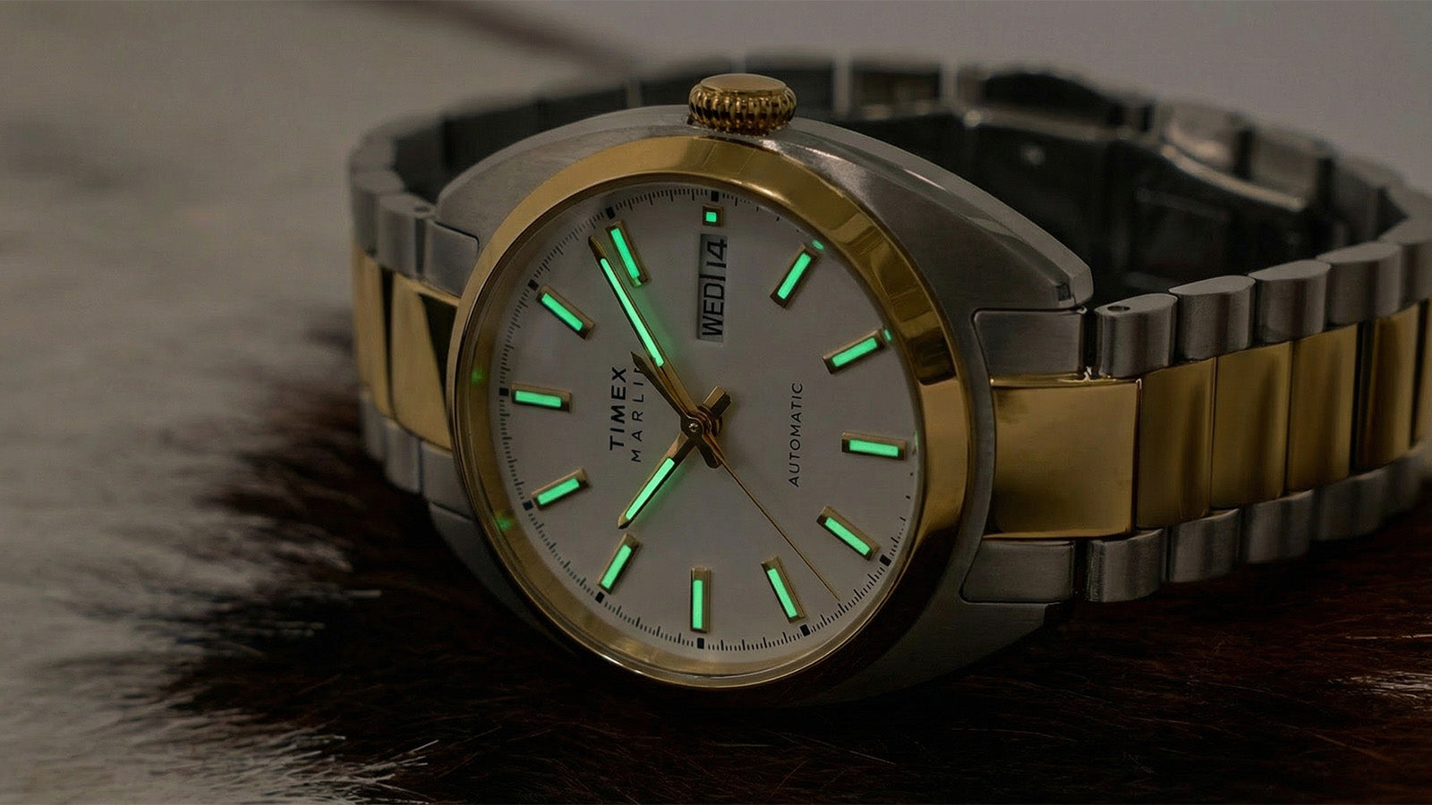 Timex Marlin® Draper Automatic watch with green-glowing luminous hour markers and hands in low light.