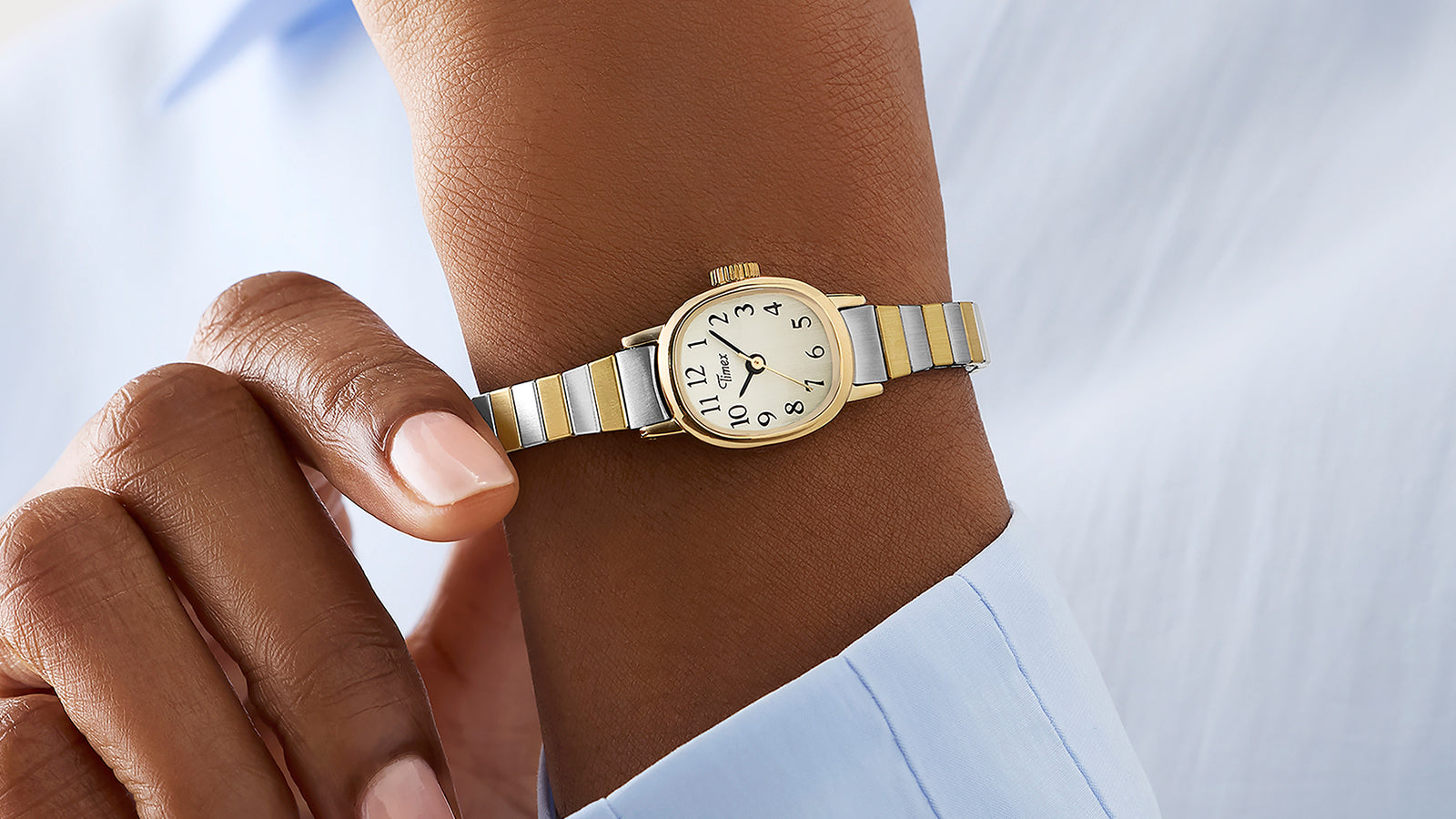 Cavatina® Mini women’s watch worn with a white shirt cuff, featuring a gold-tone case and two-tone expansion bracelet.