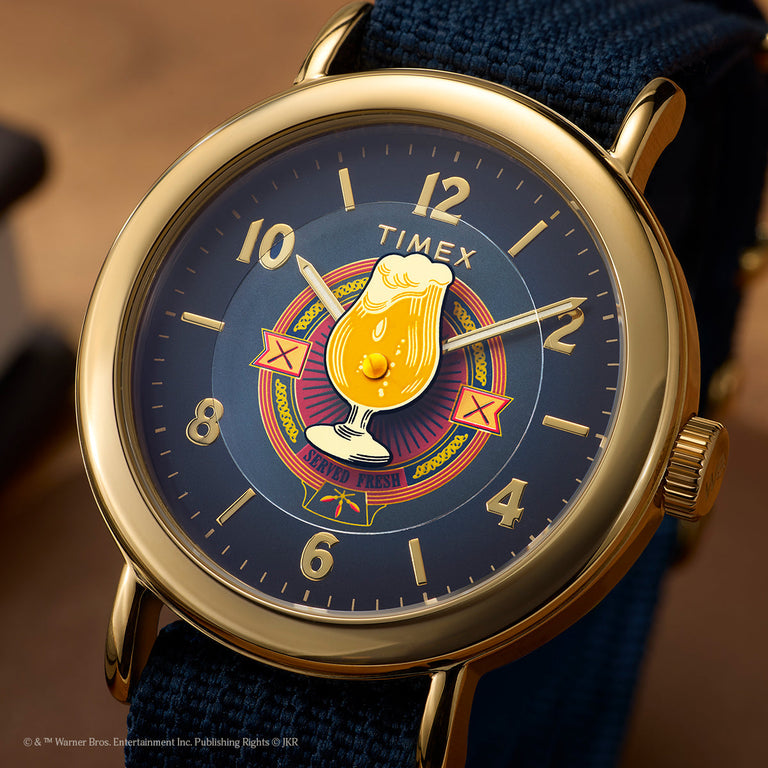Harry Potter x Timex Weekender Butterbeer watch with navy dial, gold-tone case, and Butterbeer graphic at center.