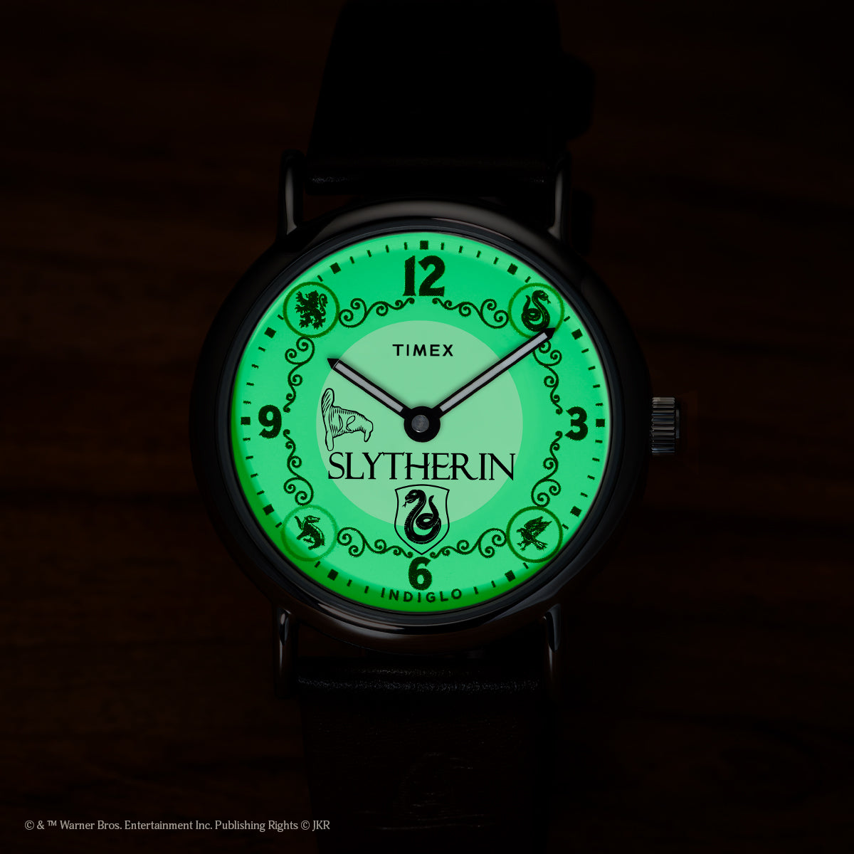 Harry Potter x Timex Weekender Slytherin watch illuminated in green INDIGLO mode showing Slytherin name and serpent crest.