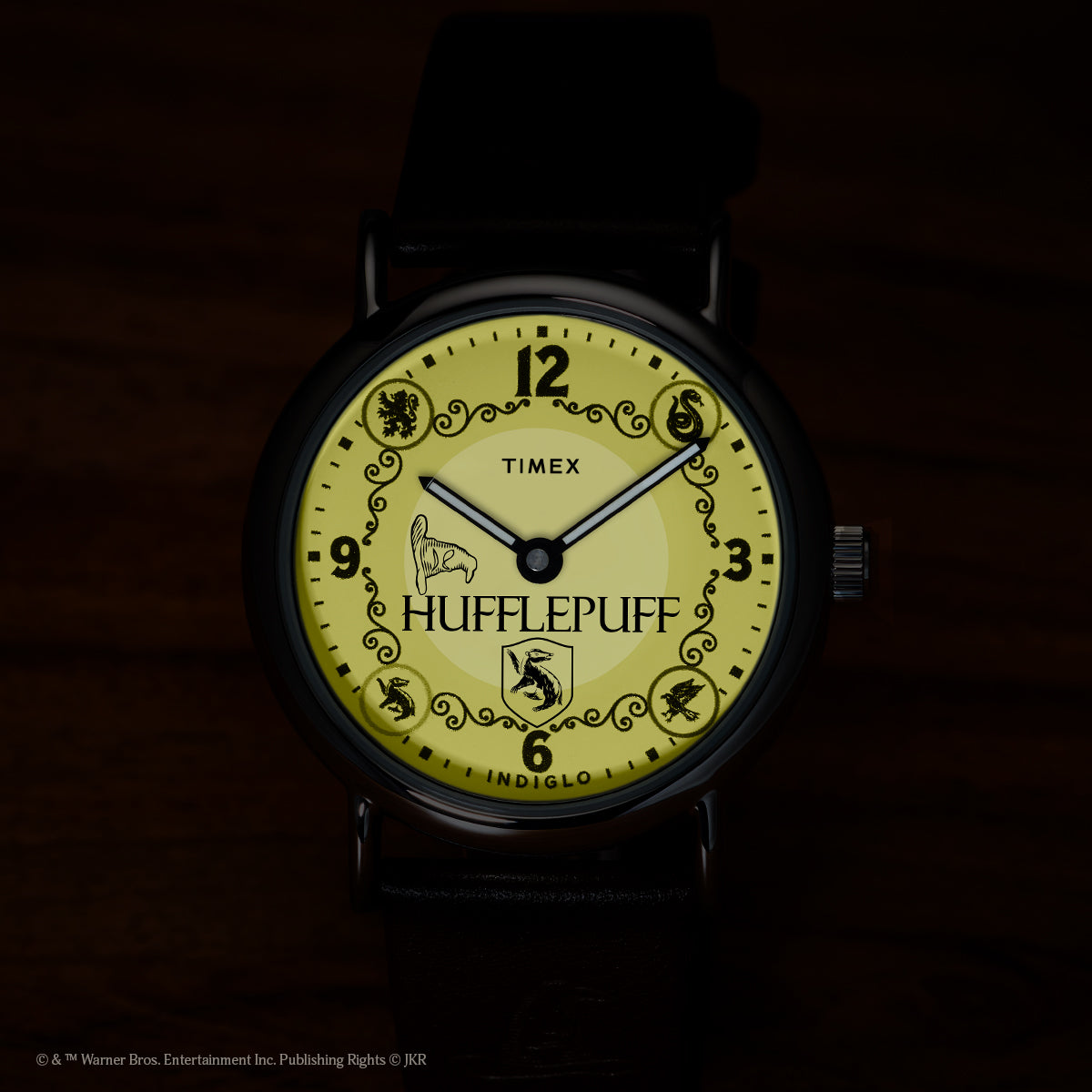 Harry Potter x Timex Weekender Hufflepuff watch illuminated in yellow INDIGLO mode showing Hufflepuff name and house crest.
