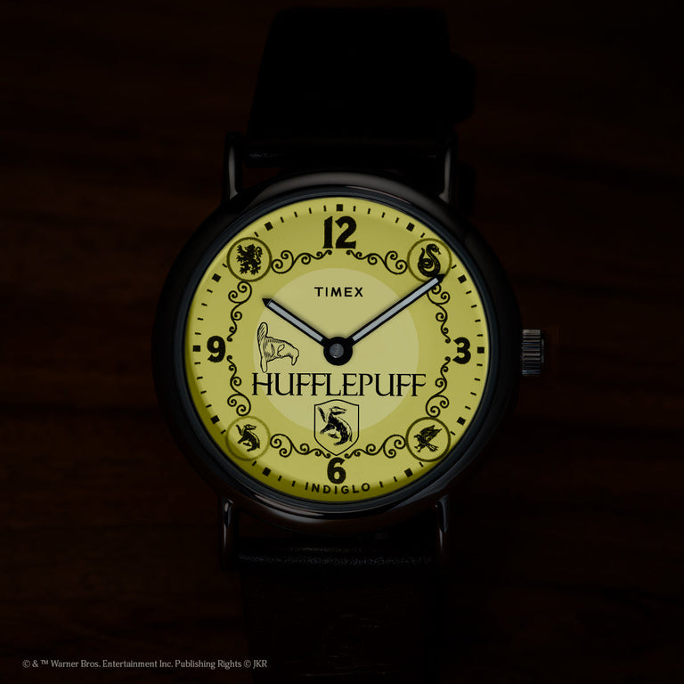 Harry Potter x Timex Weekender Hufflepuff watch illuminated in yellow INDIGLO mode showing Hufflepuff name and house crest.