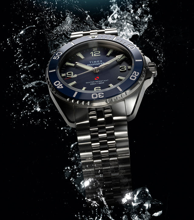 Timex Deepwater Arctic stainless steel dive watch with blue dial and rotating bezel in water splash