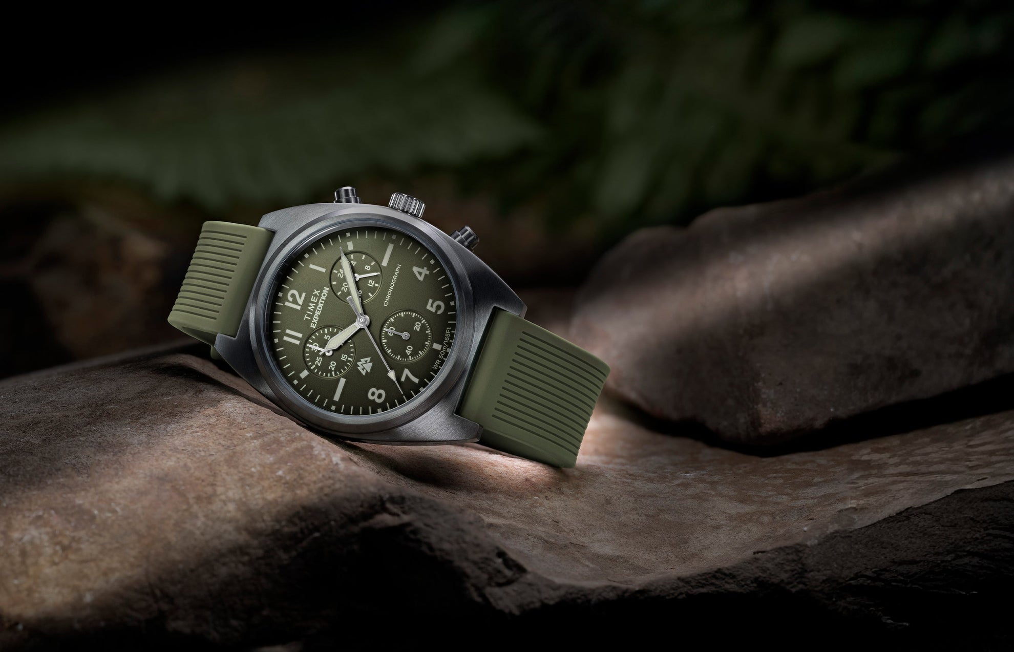 Timex Expedition Capstone Chronograph with green dial and rubber strap resting on rocks outdoors
