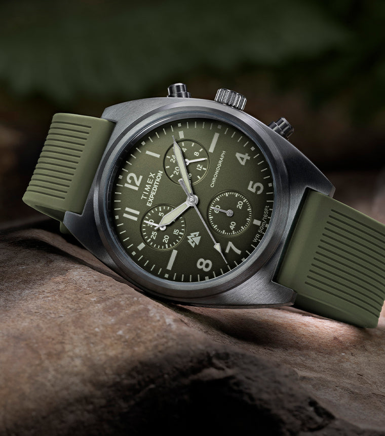 Timex Expedition Capstone Chronograph with green dial and rubber strap resting on rocks outdoors