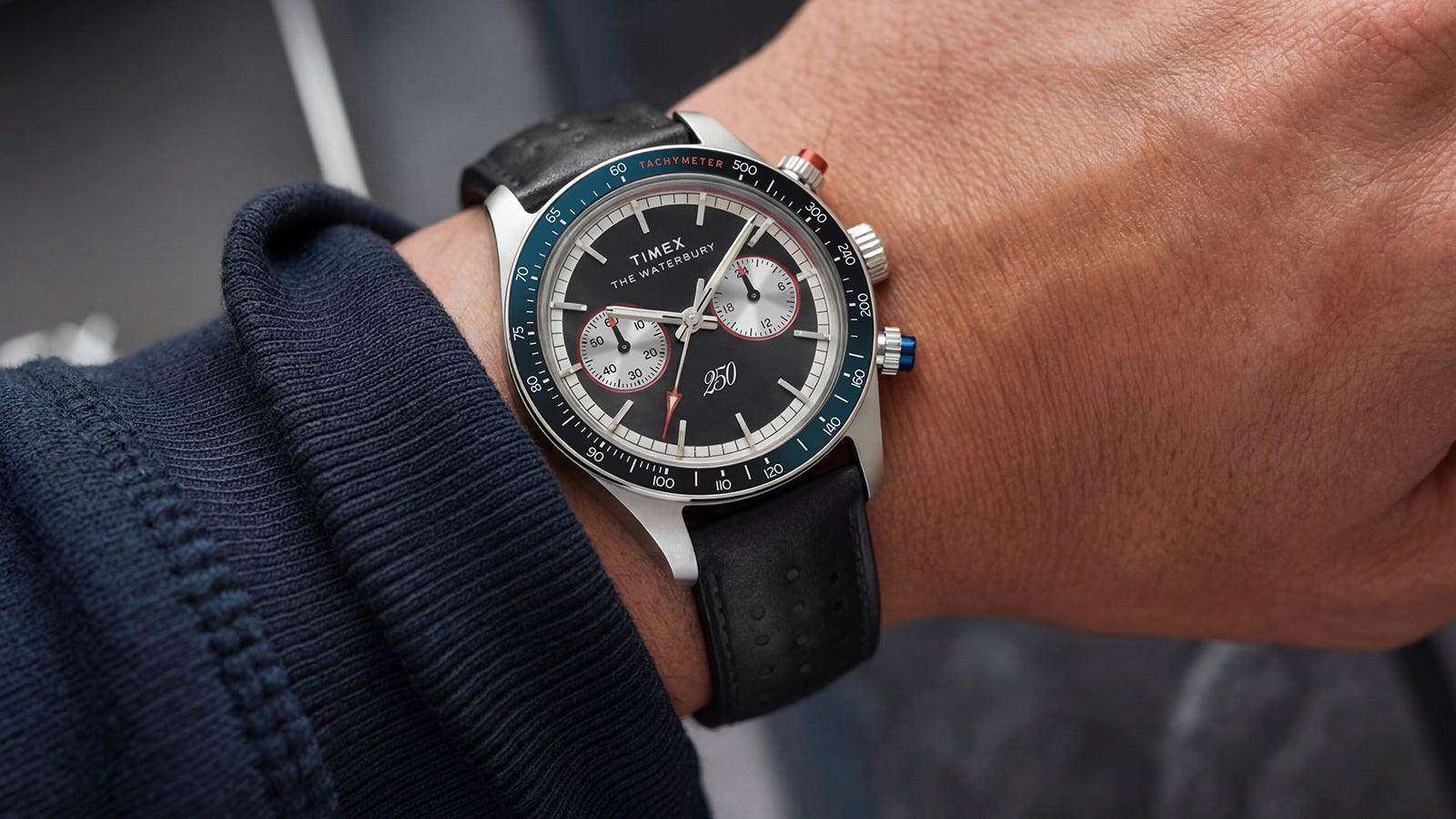 Waterbury Heritage America 250 Chronograph worn on the wrist, featuring a stainless-steel case, black dial, and perforated leather strap.