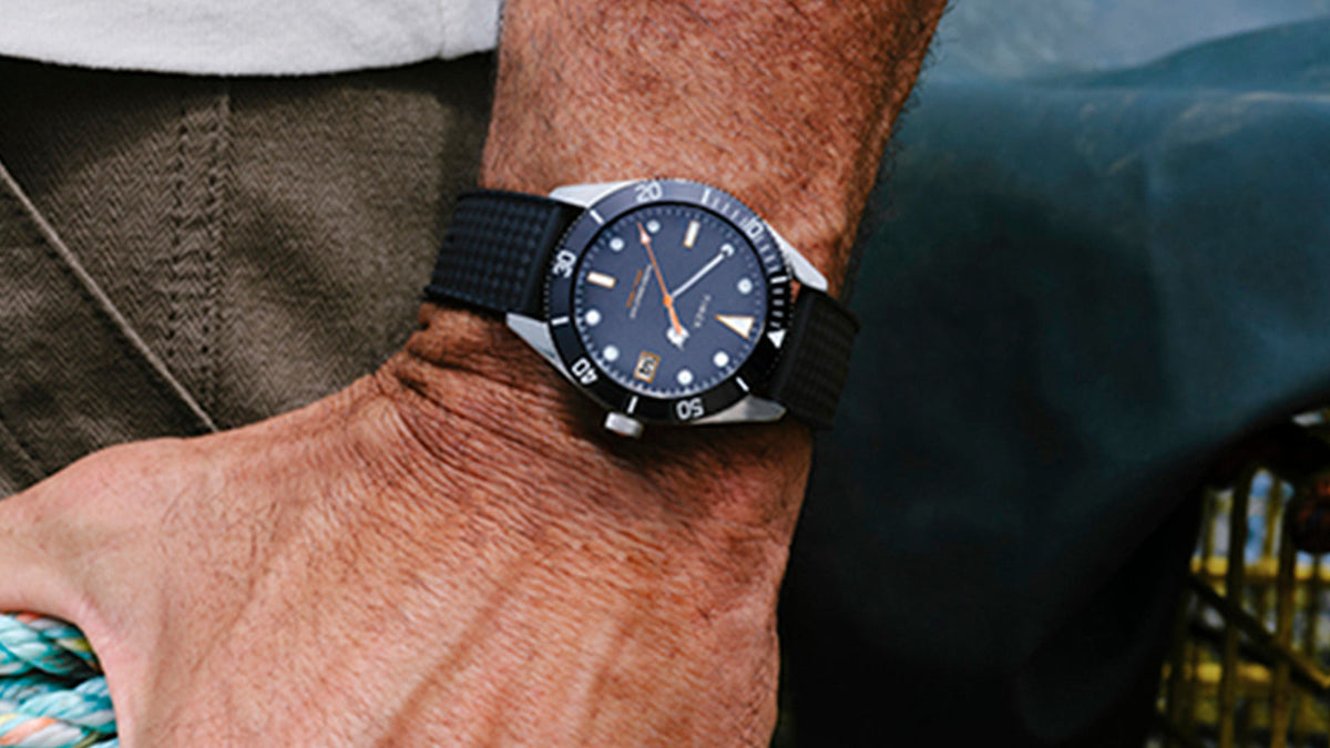 Close-up of the Bespoke Post x Timex Heritage 66 watch with a blue dial and black strap.