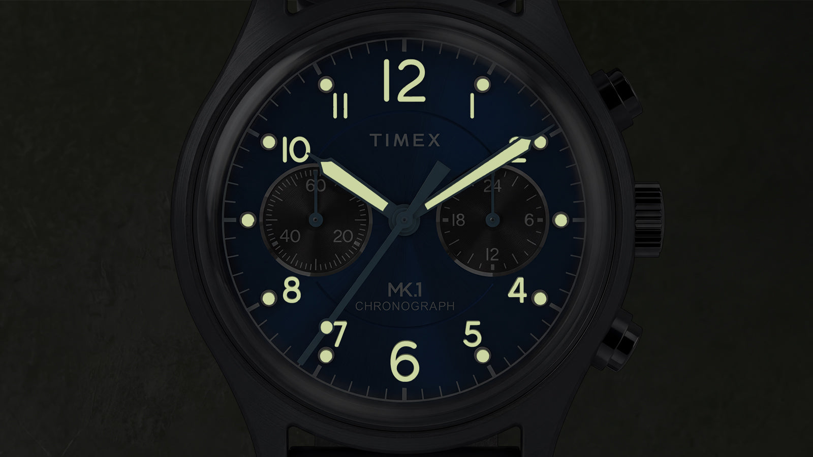 Close-up of the Timex MK1® Chronograph highlighting luminous hands, glowing hour markers, and chronograph subdials in low light.
