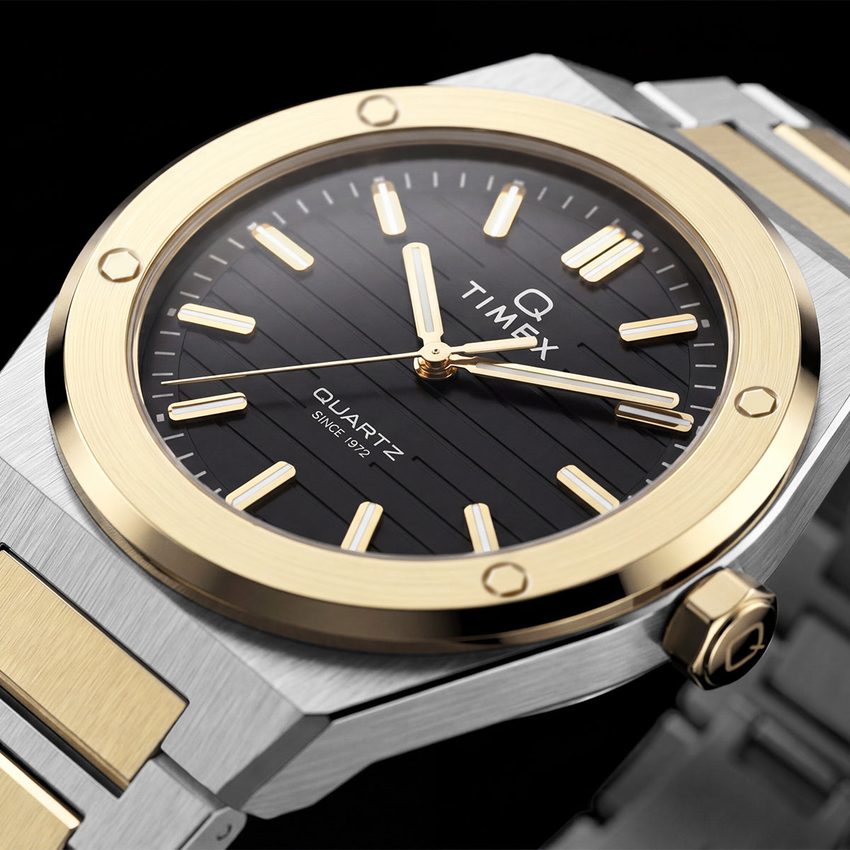 Close-up of the Timex Q Marbella black textured dial with a brushed gold-tone bezel and two-tone stainless steel bracelet.