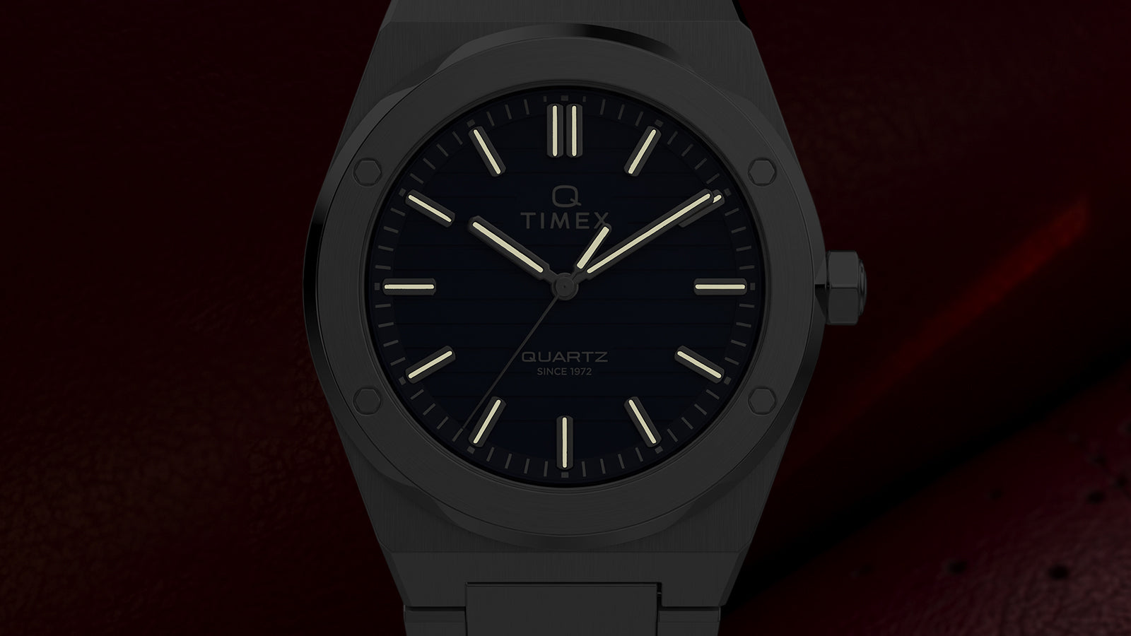 Front view of the Timex Q Marbella watch highlighting glowing hands and hour markers against a dark background.