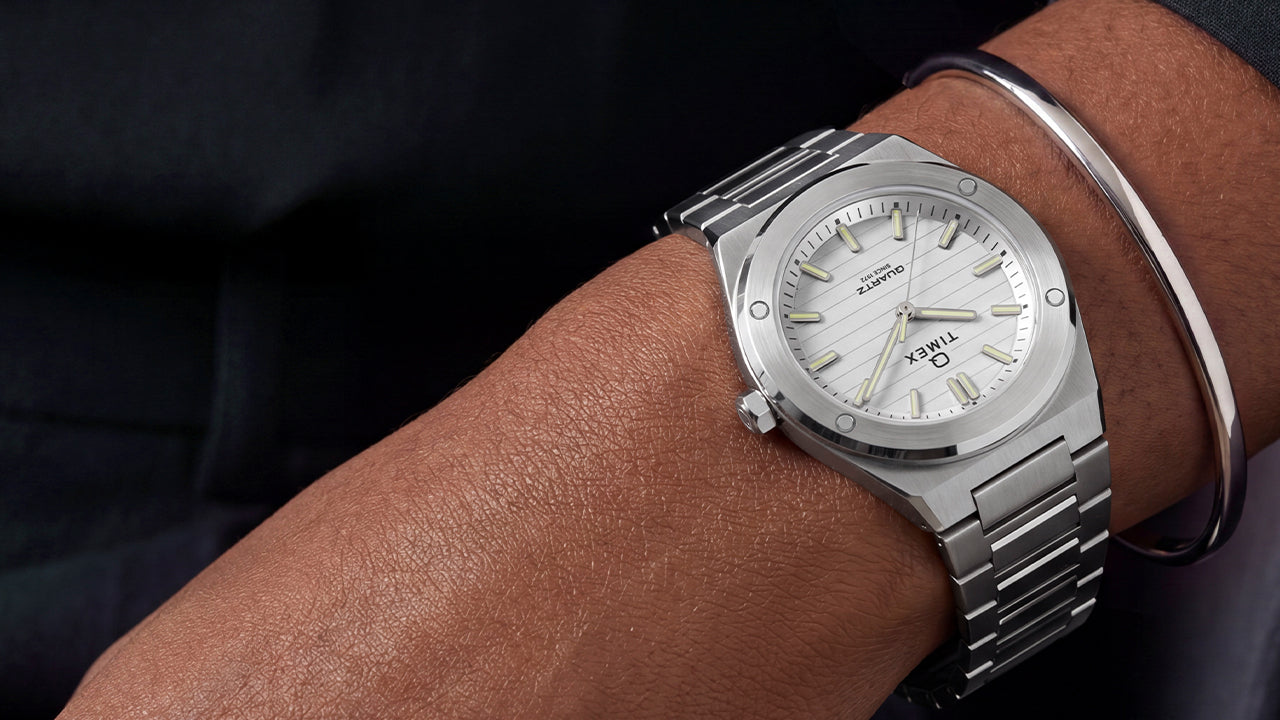 Q Timex Marbella stainless steel watch with a silver dial and integrated bracelet worn on the wrist.
