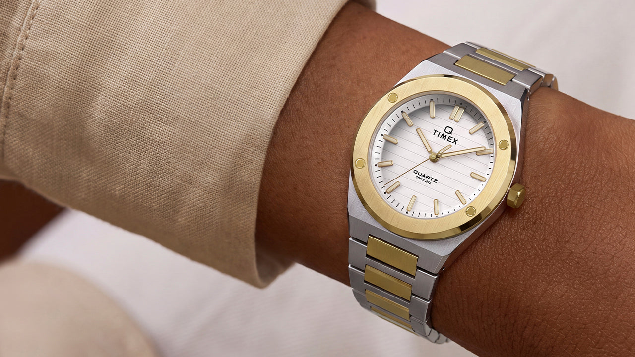 Q Timex Marbella two-tone stainless steel watch with a white dial and gold-tone bezel worn on the wrist.