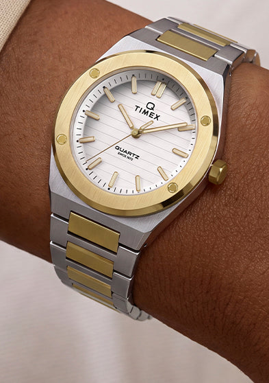 Q Timex Marbella two-tone stainless steel watch with a white dial and gold-tone bezel worn on the wrist.