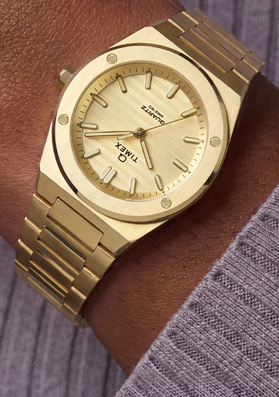 Q Timex Marbella gold-tone stainless steel watch with a champagne dial and integrated bracelet worn on the wrist.