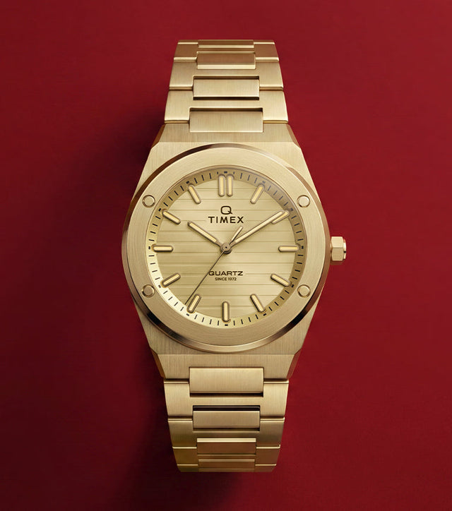 Front view of the Q Timex Marbella gold-tone stainless steel watch featuring a champagne dial and integrated bracelet.