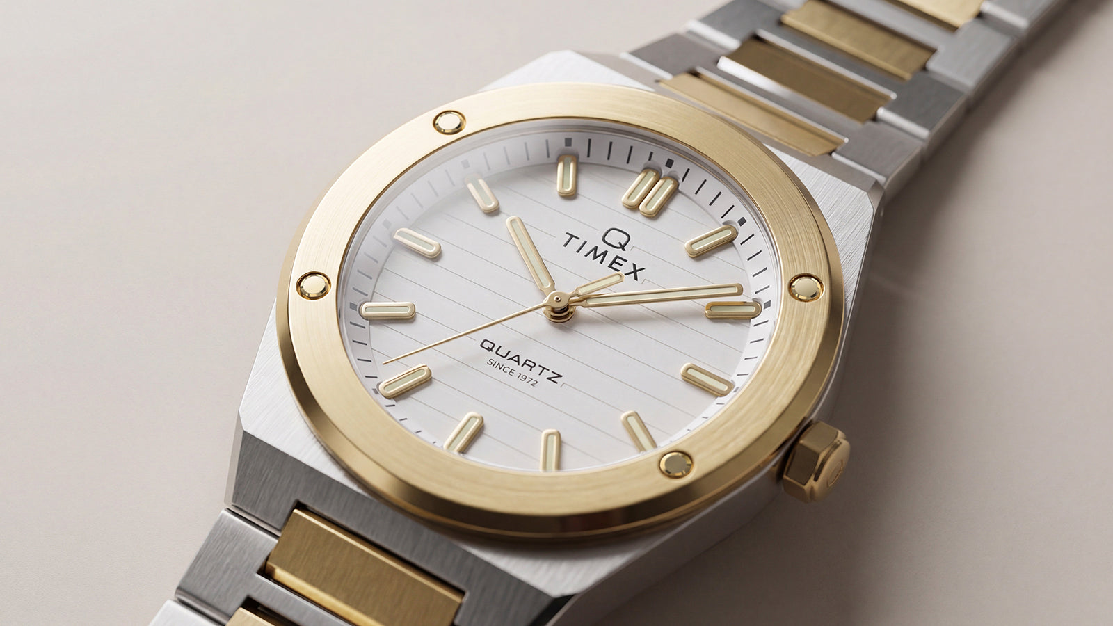 Close-up of the Q Timex Marbella two-tone stainless steel watch featuring a white dial, gold-tone bezel, and integrated bracelet.