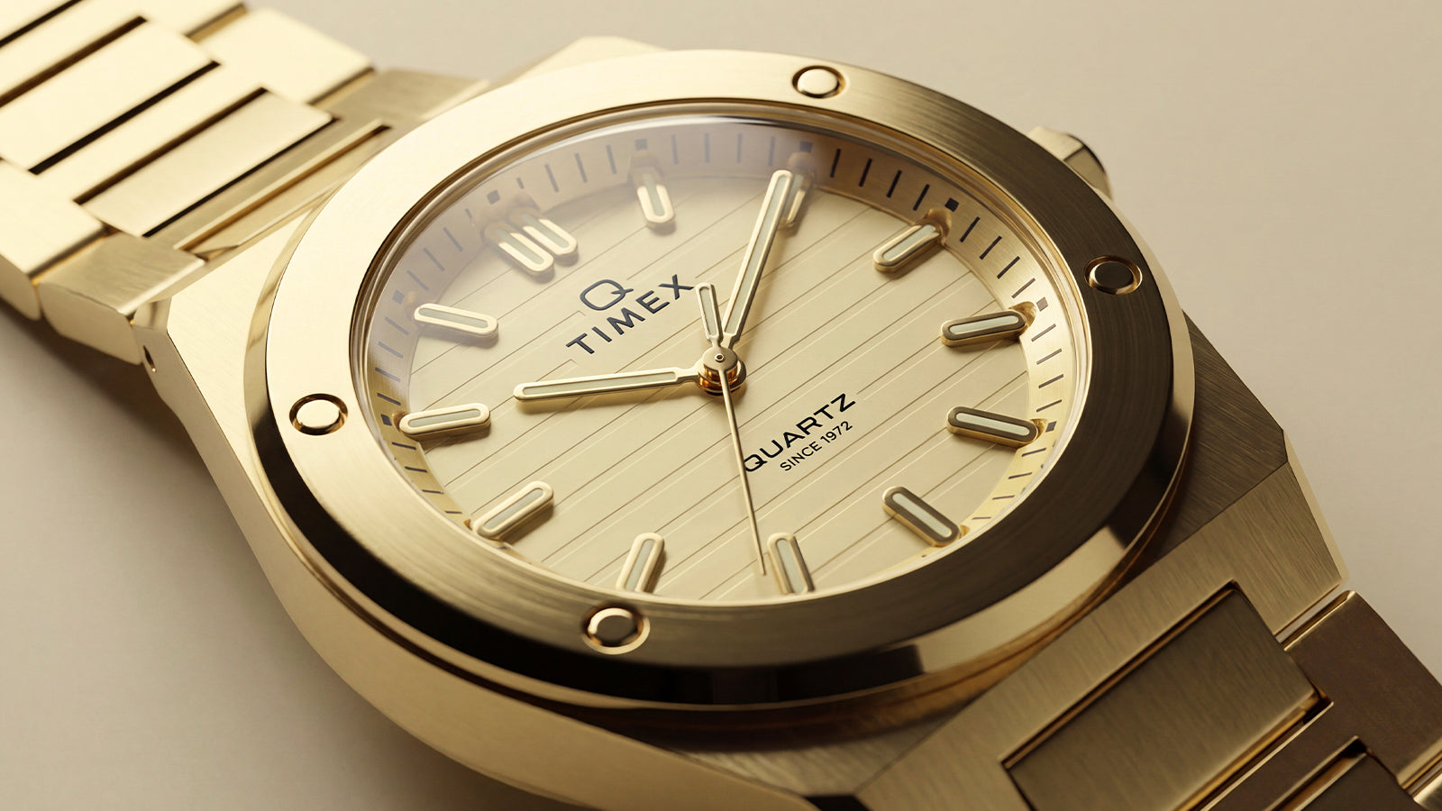 Close-up of the Q Timex Marbella gold-tone stainless steel watch with a champagne dial, brushed bezel, and integrated bracelet.
