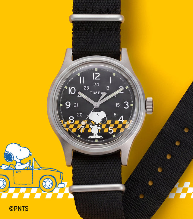 Peanuts® x Timex MK1® watch with a black fabric strap, black dial featuring Snoopy in sunglasses, and a yellow racing-inspired background with checkered graphics.