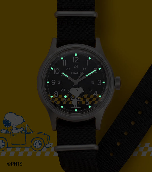 Peanuts® x Timex MK1® watch with INDIGLO® night-light illuminating the hands and hour markers, featuring Snoopy artwork on the black dial.
