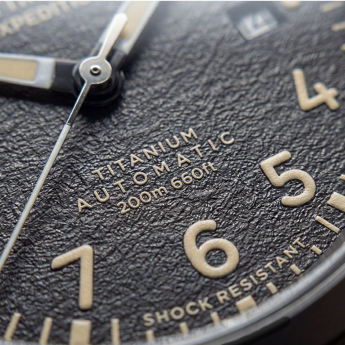 Close-up of the Expedition® Field Post Automatic textured black dial showing automatic movement, 200m water resistance, and shock resistance.