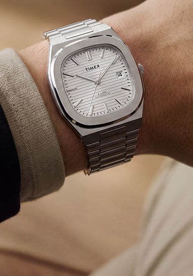 Close-up of the Timex® Automatic E Line 38mm stainless steel watch with a silver textured dial and date window worn on the wrist.