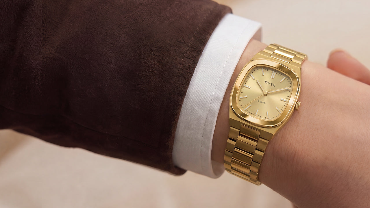 Close-up of the Timex® Quartz E Line 30mm gold-tone stainless steel watch with a champagne dial worn on the wrist.