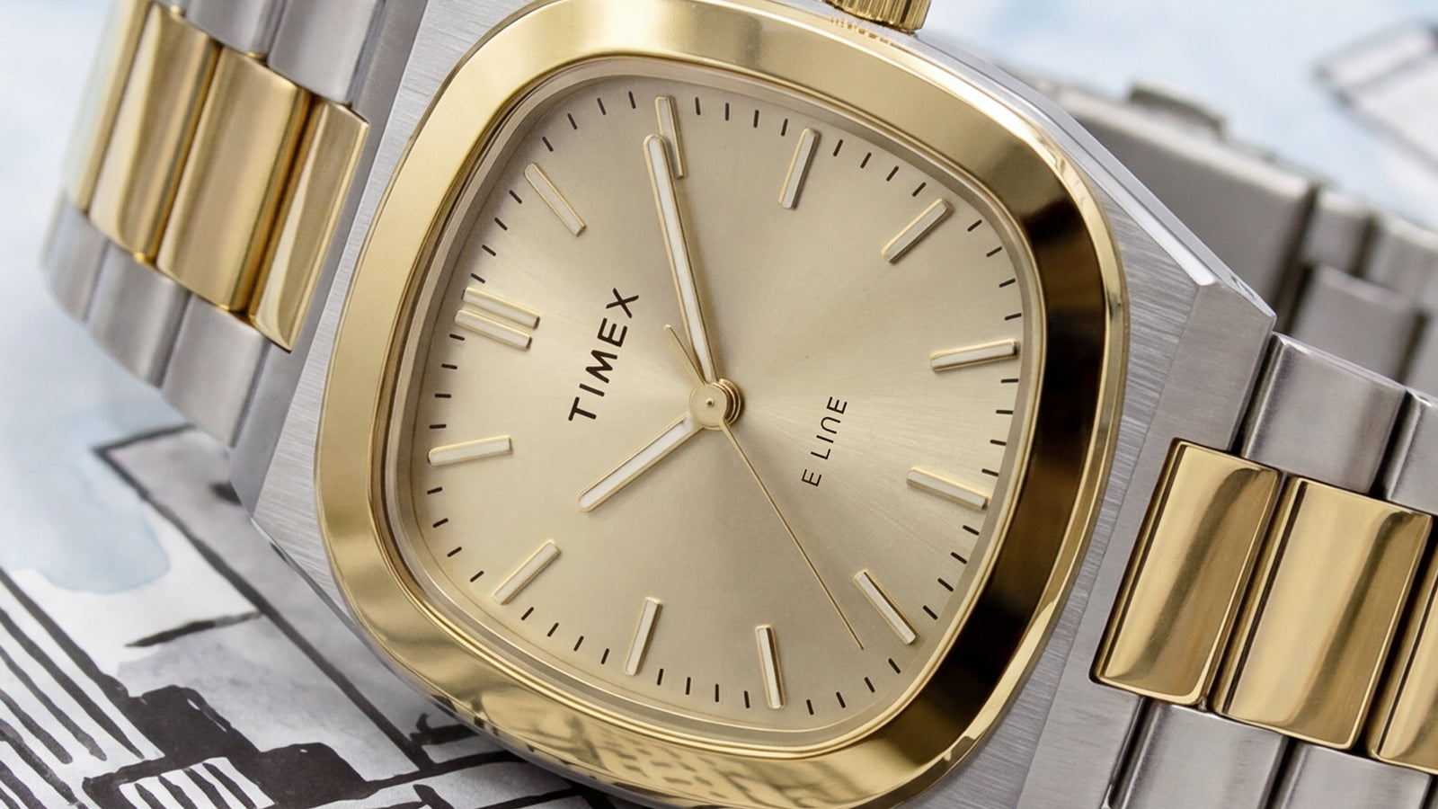 Close-up of the Timex® Quartz E Line 30mm featuring a champagne sunray dial, polished gold-tone bezel, and two-tone stainless steel bracelet.