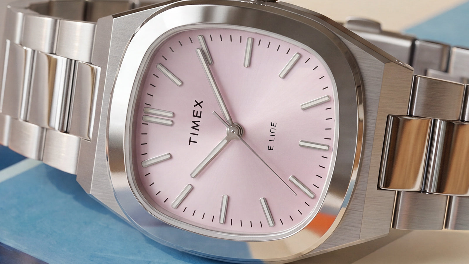 Close-up of the Timex® Quartz E Line 30mm featuring a soft pink sunray dial, polished stainless steel case, and stainless steel bracelet.