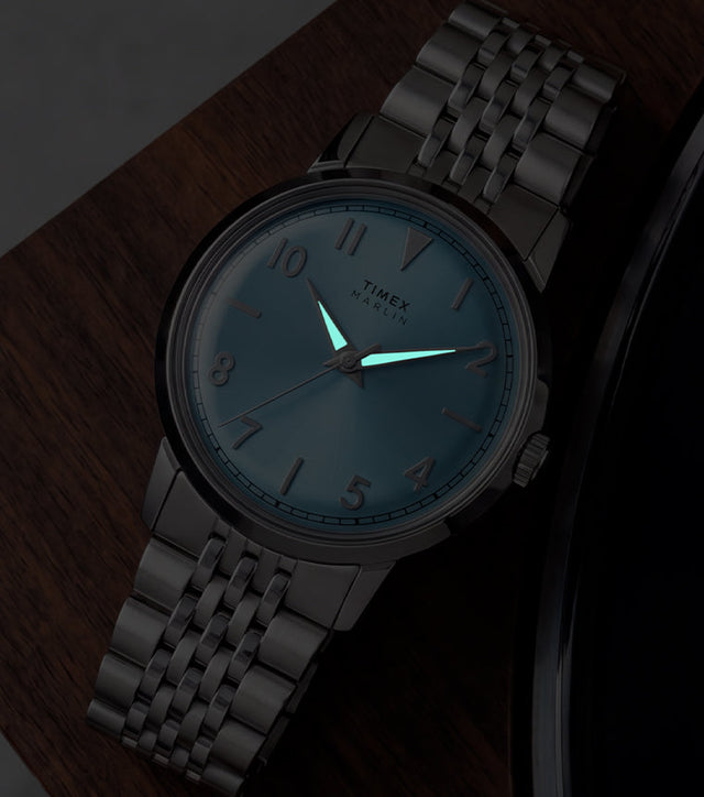Timex Marlin Quartz watch with luminous hands glowing in low light beside a vinyl record.