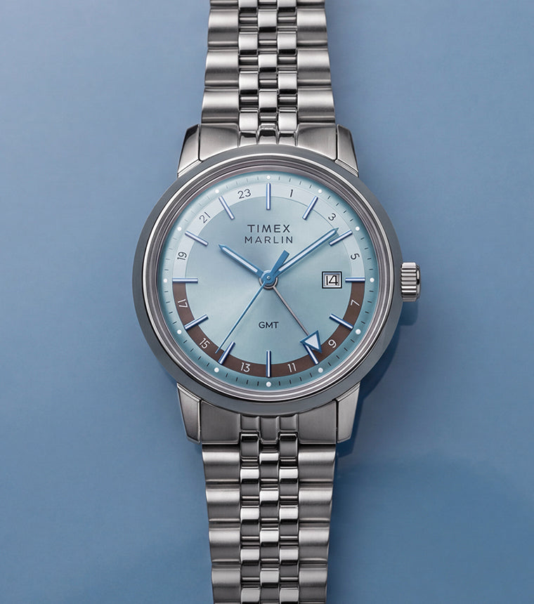 Marlin® Quartz GMT with an icy blue dial and stainless-steel bracelet displayed on a blue surface.
