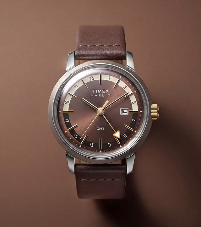 Marlin® Quartz GMT with a brown dial and leather strap displayed against a warm brown background.