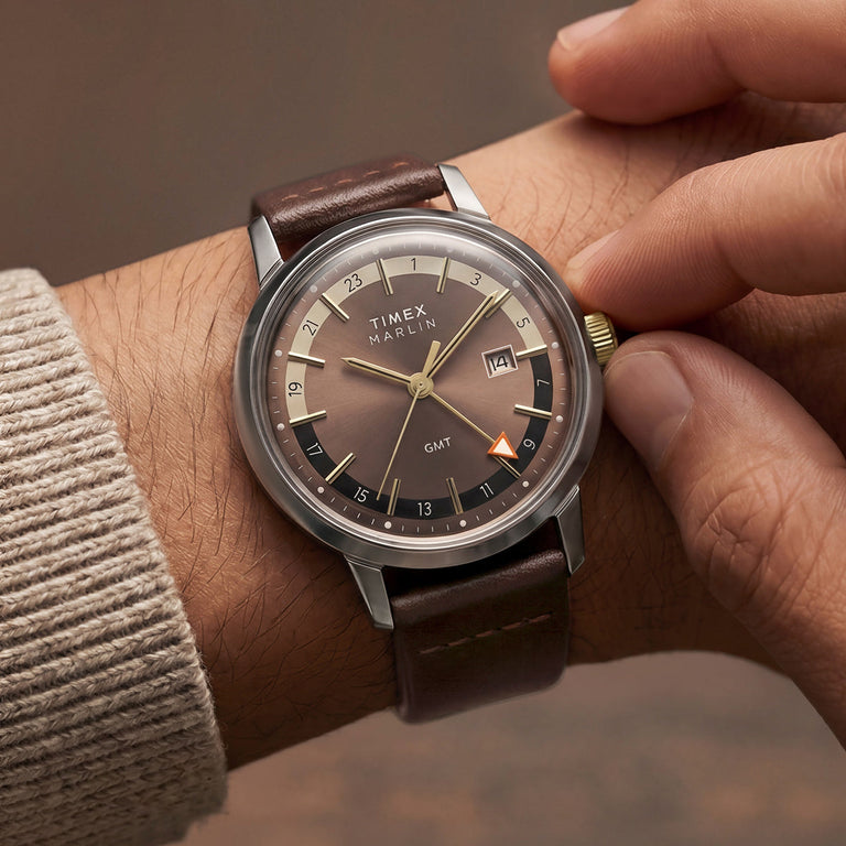 Marlin® Quartz GMT worn on the wrist as the wearer adjusts its gold-tone crown.
