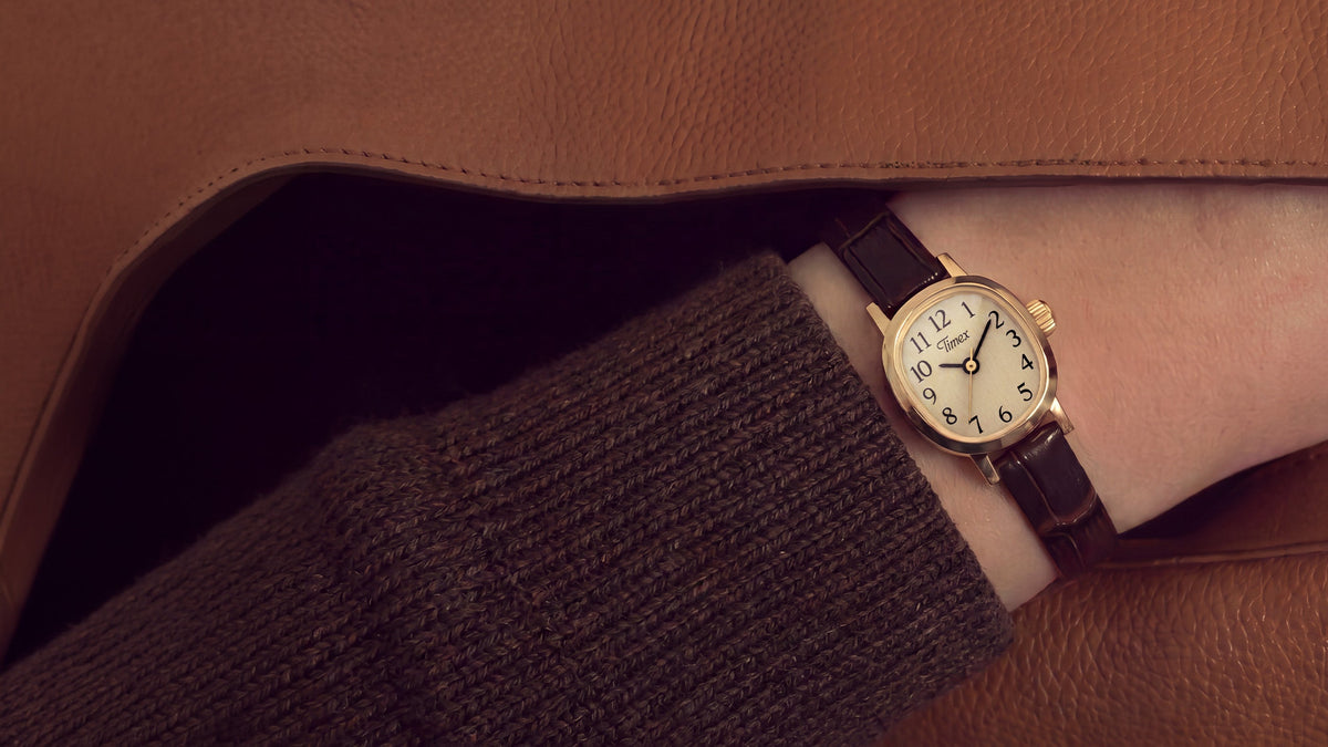 Cavatina® Mini watch worn on a wrist beneath a brown knit sleeve and tan coat.