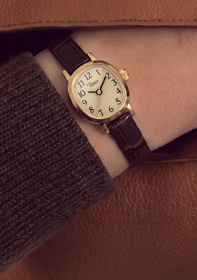 Cavatina® Mini watch worn on a wrist beneath a brown knit sleeve and tan coat.