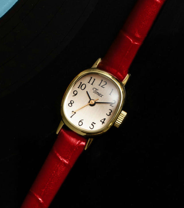 Cavatina® Mini watch with a gold-tone case, champagne dial, and red leather strap displayed on a vinyl record.