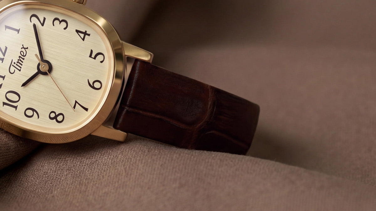 Cropped close-up of the Cavatina® Mini resting on folded brown fabric, highlighting its dial and textured leather strap.