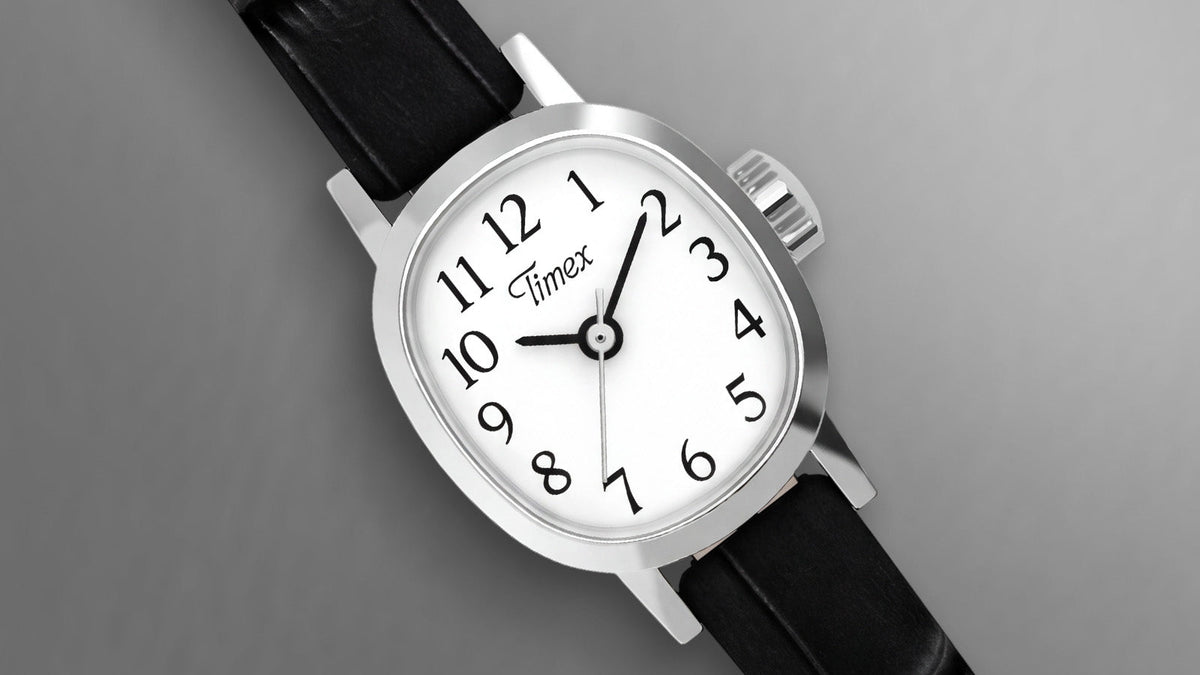 Close-up of the Cavatina® Mini featuring a silver-tone case, white dial, black Arabic numerals, and black leather strap.