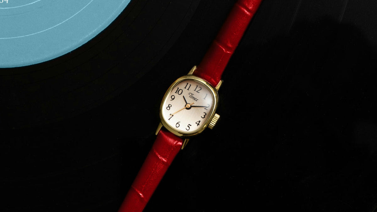 Cavatina® Mini watch with a red leather strap displayed diagonally across a black vinyl record.