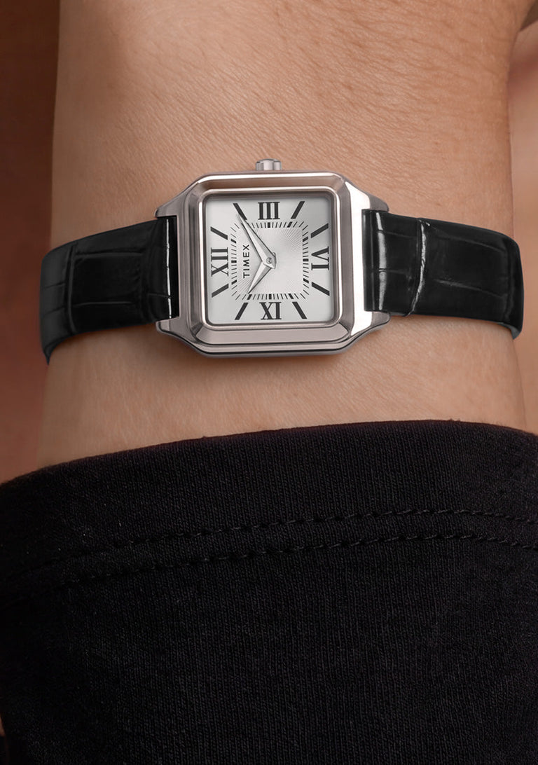 Timex Addison watch with a silver-tone rectangular case and black leather strap worn on the wrist.