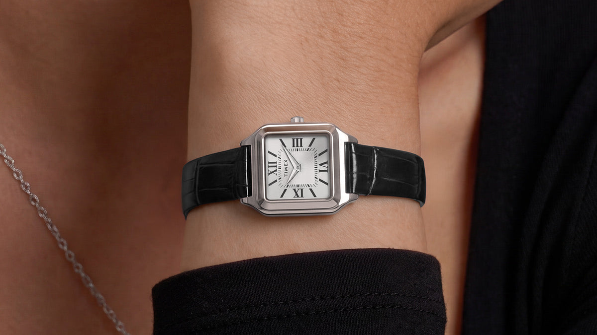 Close-up of the Timex Addison watch styled on the wrist with a black outfit and silver necklace.