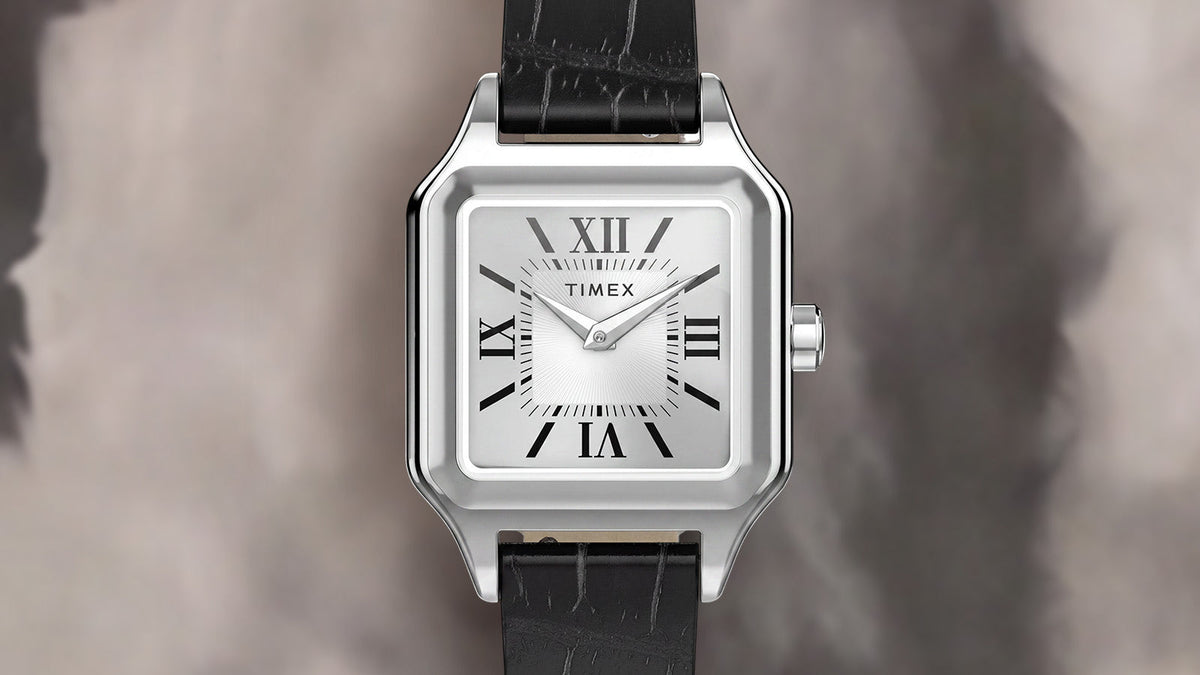 Front view of the Timex Addison watch featuring a silver-tone rectangular case, white dial, black Roman numerals, and black leather strap.