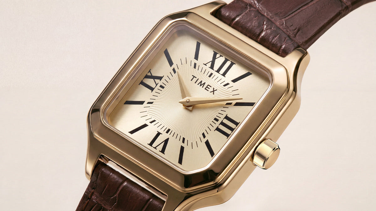 Detailed view of the Timex Addison watch featuring a gold-tone rectangular case, champagne dial, Roman numerals, and brown leather strap.