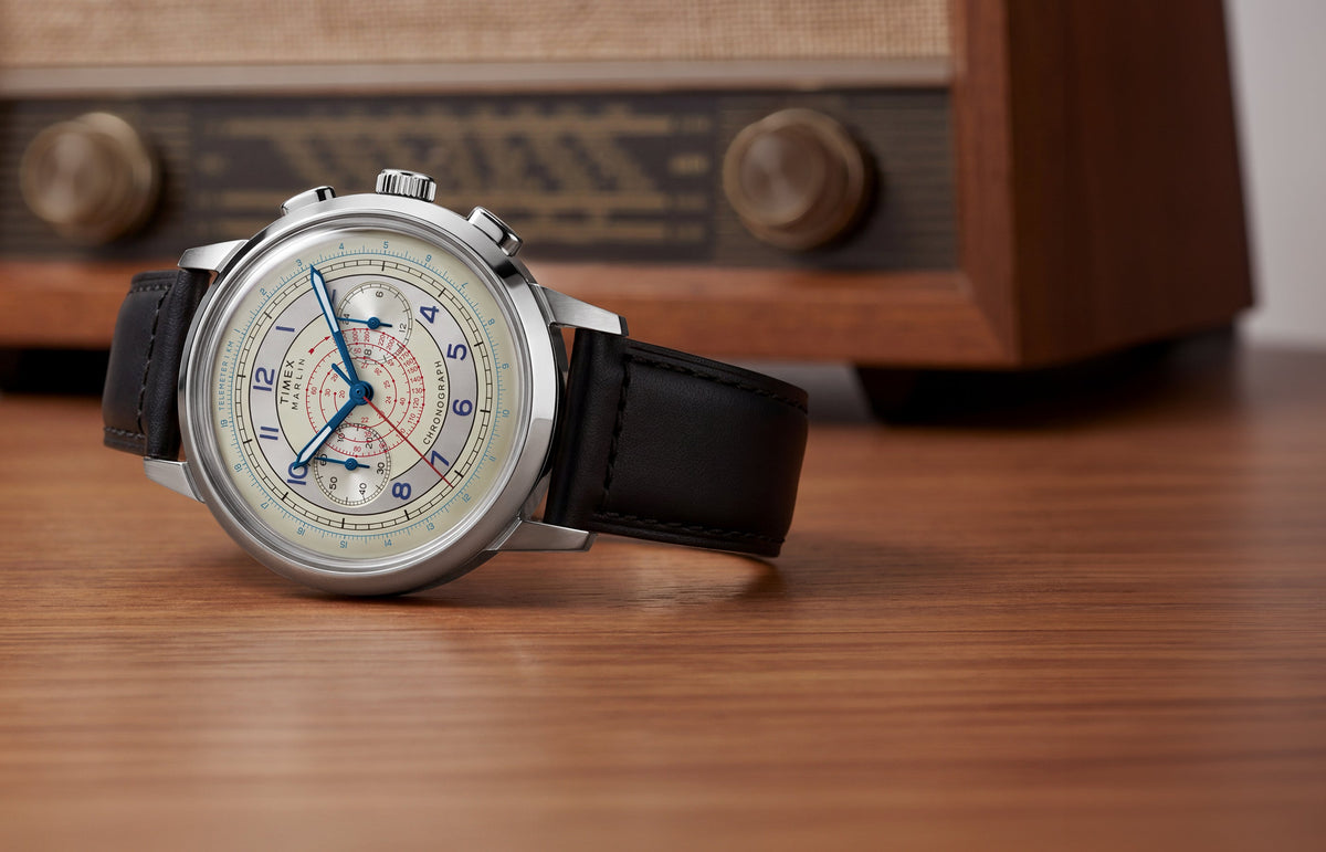 Marlin® Neo Classic Chronograph with a cream multiscale dial and black leather strap displayed on a wooden surface beside a vintage radio.
