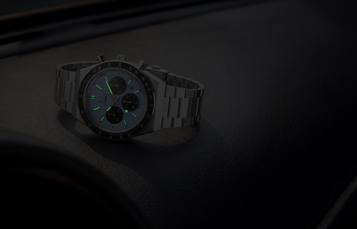 Q Timex Chronograph in low light, highlighting its glowing hands and hour markers.