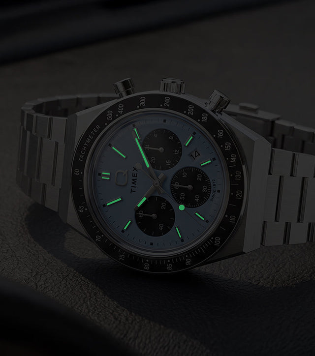 Q Timex Chronograph in low light, highlighting its glowing hands and hour markers.