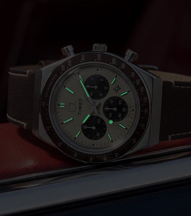 Q Timex Chronograph in low light, highlighting its glowing hands and hour markers.
