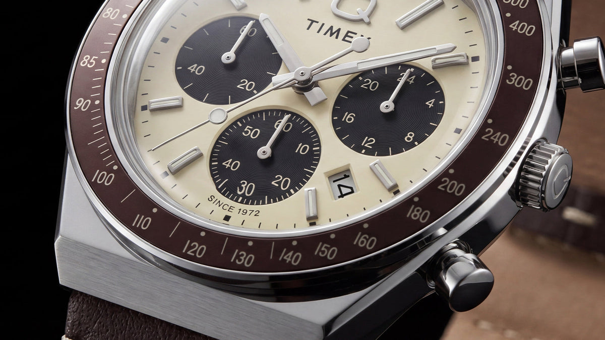 Close-up of the Q Timex Chronograph’s cream dial, black subdials, date window, and brown tachymeter bezel.
